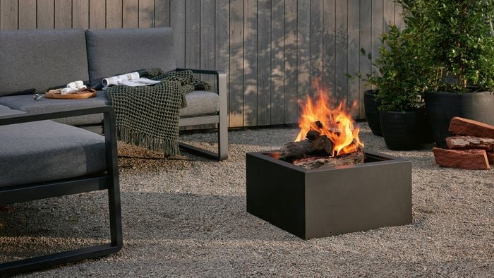 An outdoor setting and a fire pit outside on a pebbled area.