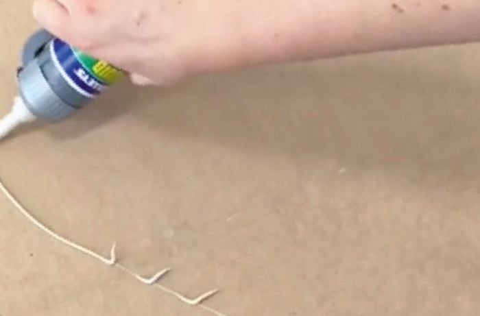 Hand applying adhesive to back of panel.