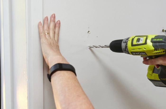 A person drilling holes in a plasterboard wall