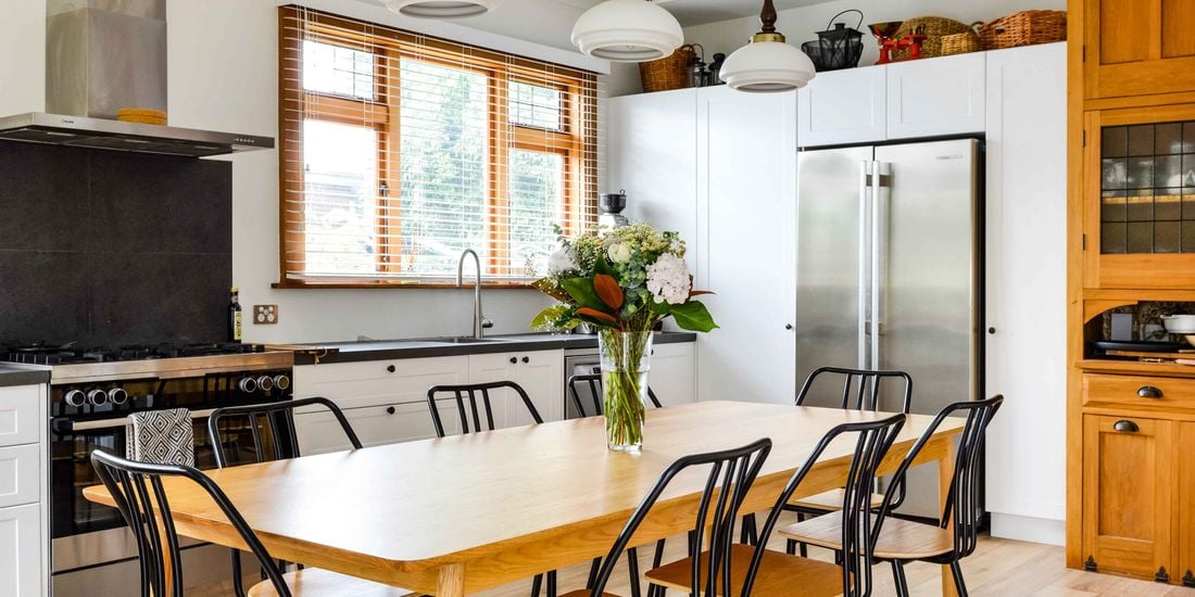Neat and clean kitchen with a dining table with a vase of flowers