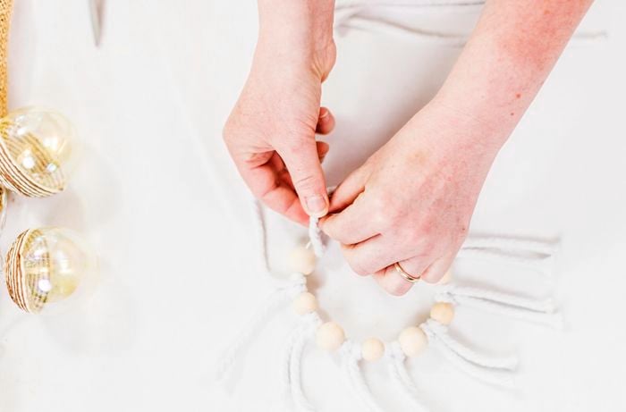 A person attaching cord to a macrame decoration