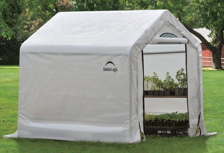 Potted plants inside a portable greenhouse with shelves