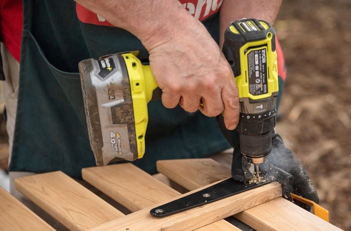 A Bunnings Team Member holding a drill against a piece of timber