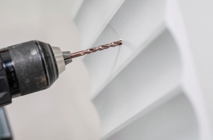 Holes being drilled into a scallop panel with a power drill