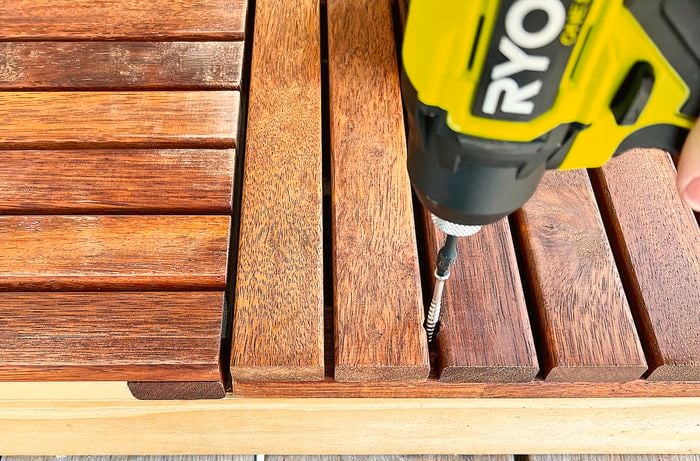 Person attaching wooden side panels to frames with a drill.