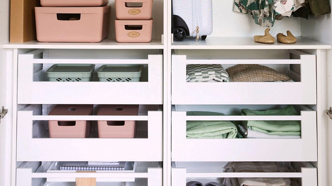 Stackable containers, a suitcase, clothing and linen in a built-in wardrobe