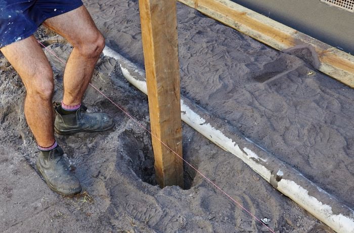 A fence post being positioned into a posthole