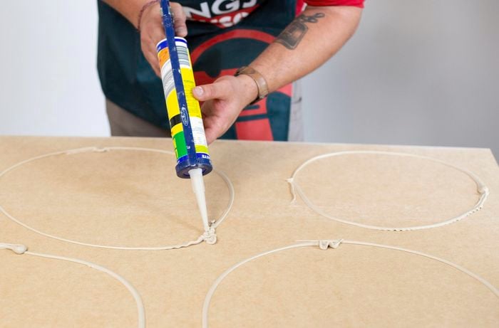 Person using liquid nails on the back of VJ feature wall panel so it will stick to wall.