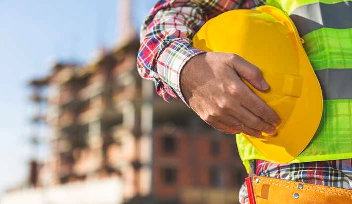 Construction worker holding a hard hat on a construction site