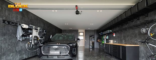 Modern garage featuring a black SUV, polished speckled flooring, wall-mounted storage, bicycles and built-in cabinetry.