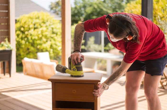 A Bunnings team member is sanding a bedside table top.