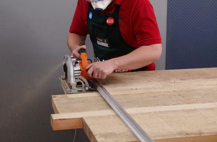 Lengths of timber for a tabletop being cut to uniform size with a circular saw and straight edge clamp