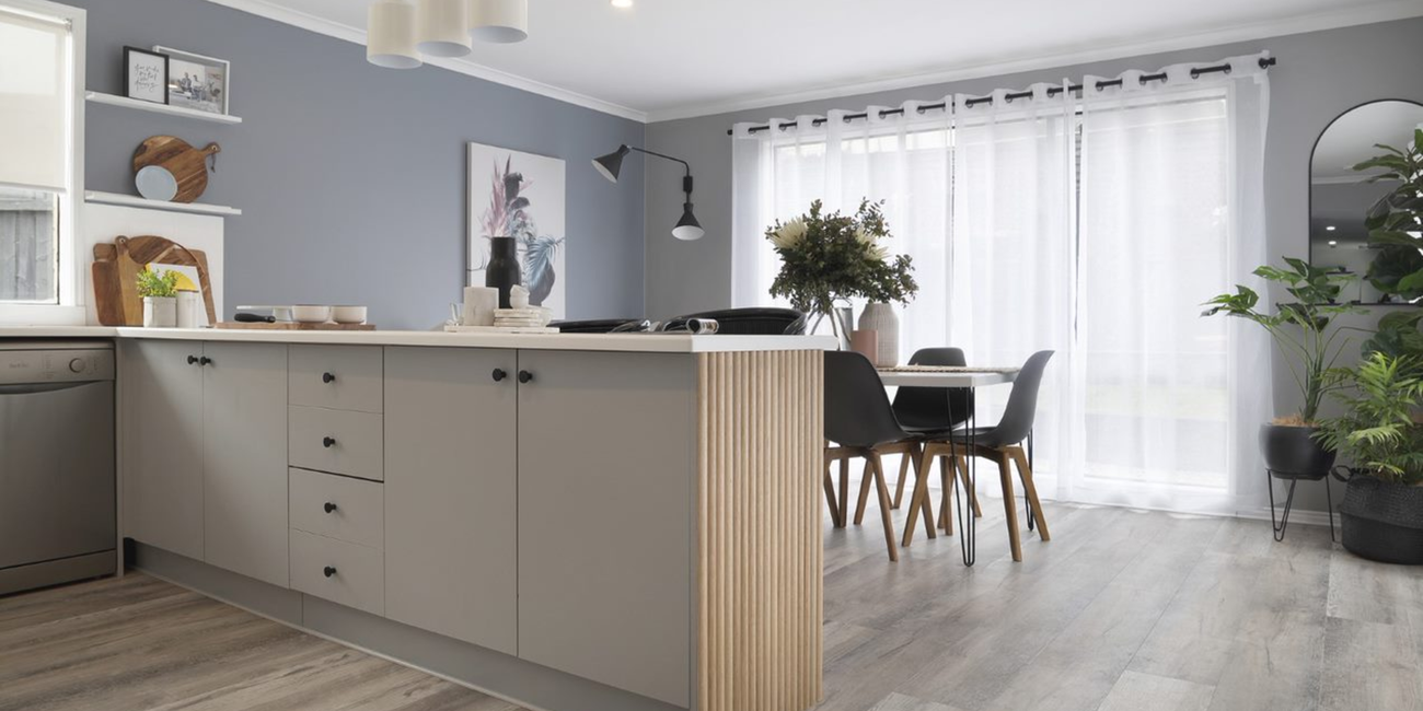 Renovated kitchen with timber floors, grey cabinets and white benchtops.