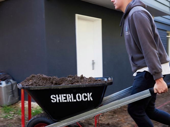 Tradesperson carting soil in wheelbarrow
