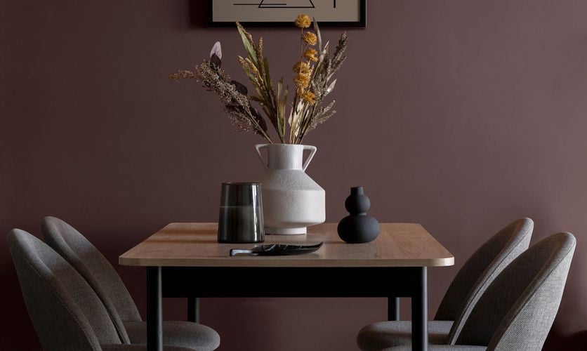 A dining table with chairs and a painting on the wall in a room.