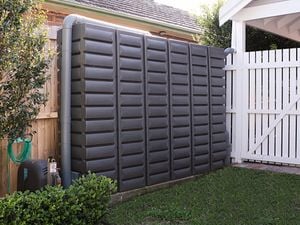 Water tank in the backyard near wooden fence.