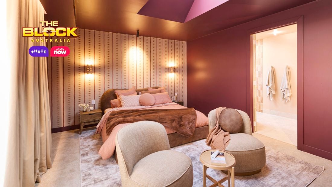 : Bright bedroom with curved headboard, warm lighting, and red accents.