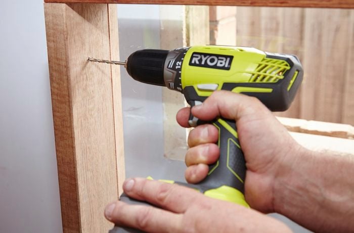 Drilling pilot holes into the window frame