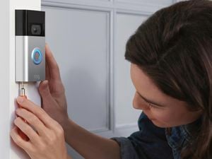 A woman installs a security camera doorbell