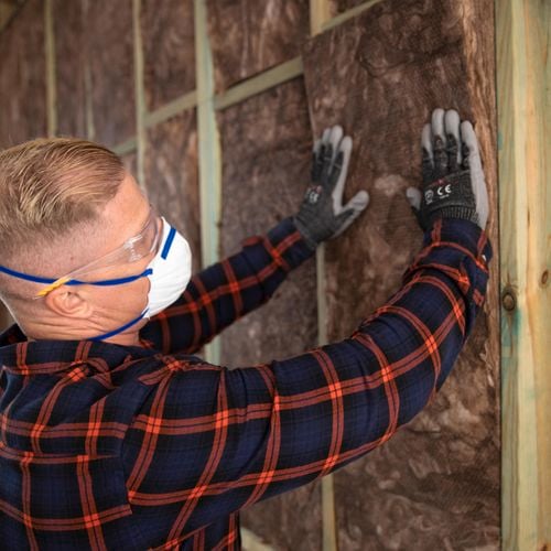 Man pushing in insulation wearing ppe.