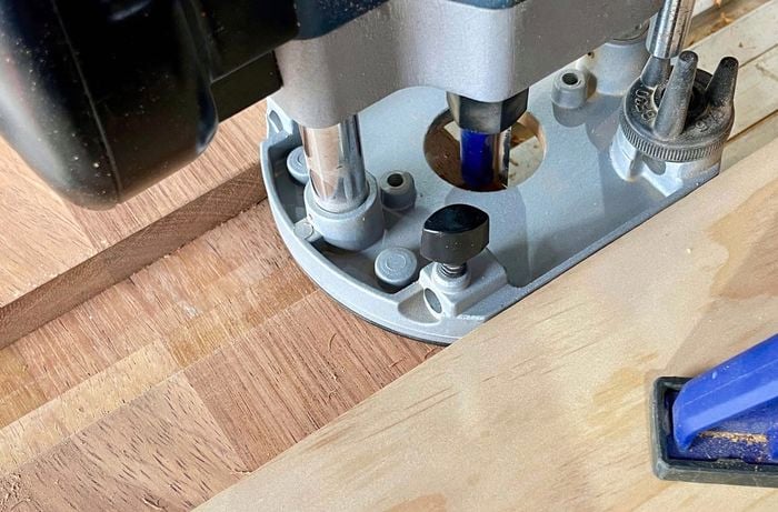 Router makes rectangular groove on plank of wood