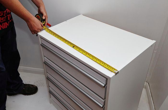 Person using measuring tape to measure length of wardrobe insert unit.