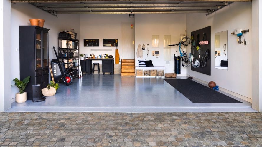 Wide shot of a garage makeover, featuring an epoxy floor, storage units and gym equipment