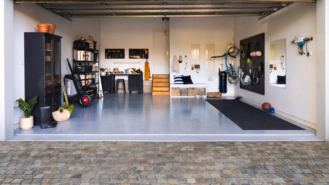 Wide shot of a garage makeover, featuring an epoxy floor, storage units and gym equipment