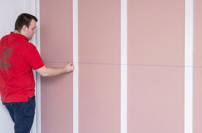 A Bunnings Team Member is measuring and marking for the horizontal battens using a chalk line. 
