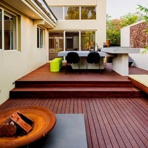 Decking with an outdoor table, outdoor bench and chairs on it at the back of a house.