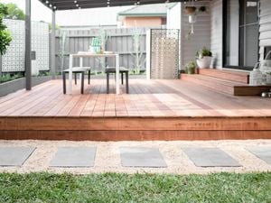 Close up of a finished stepping stone pathway beside a deck in a backyard.