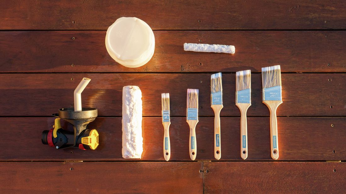 : Paint brushes, rollers and a spray gun arranged for cleaning