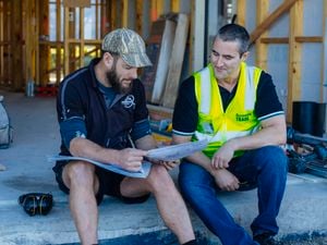 trade manager chatting with trade customer, sitting on a job site looking at plans