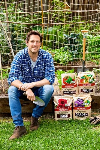 Man sitting in garden next to bags of Richgro plant food