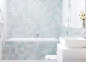 A modern bathroom with light-coloured tiles, featuring a skylight, shower, bathtub, vanity with a white basin, and a toilet.