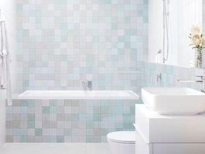 A modern bathroom with light-coloured tiles, featuring a skylight, shower, bathtub, vanity with a white basin, and a toilet.