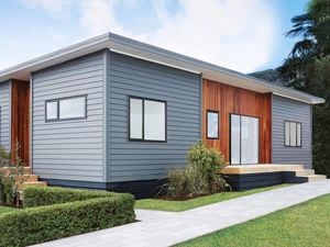 Light blue weatherboard house with a dark timber feature wall along the front entrance. There is a path leading to the house with a lush green lawn in shot.