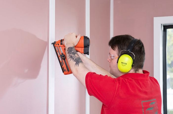 A Bunnings Team Member is attaching the vertical battens to the wall using nails.