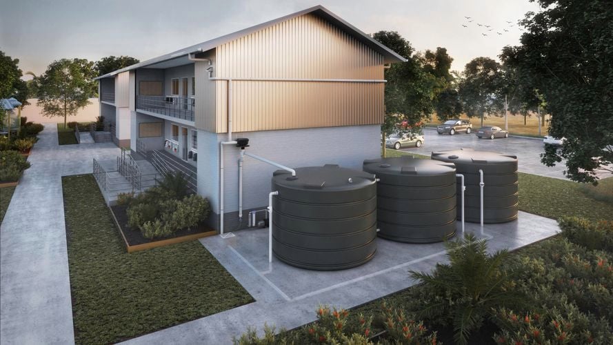 Two storey building with three large round water tanks on the side of building with car park at the back.