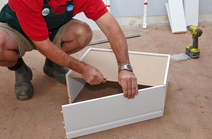 Person sliding bottom panel of wardrobe drawer in place.