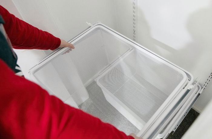 Person sliding storage organiser into cupboard