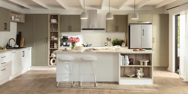 Neutral themed kitchen styled with stools, pendants, island benchtop and timber flooring .