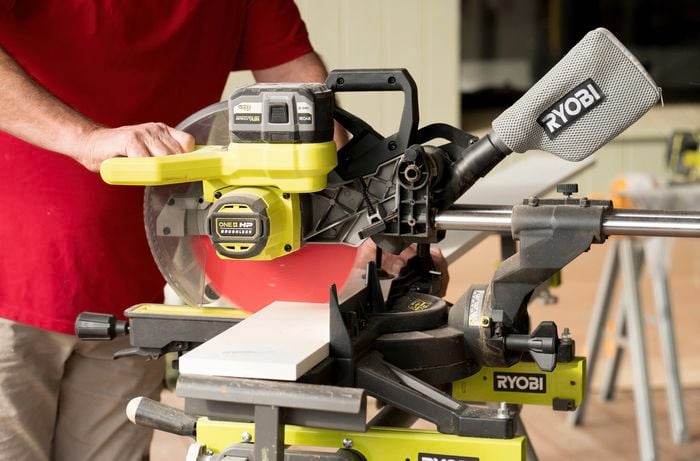 A person in a red t-shirt is cutting the kickboard to the needed length using a circular saw.