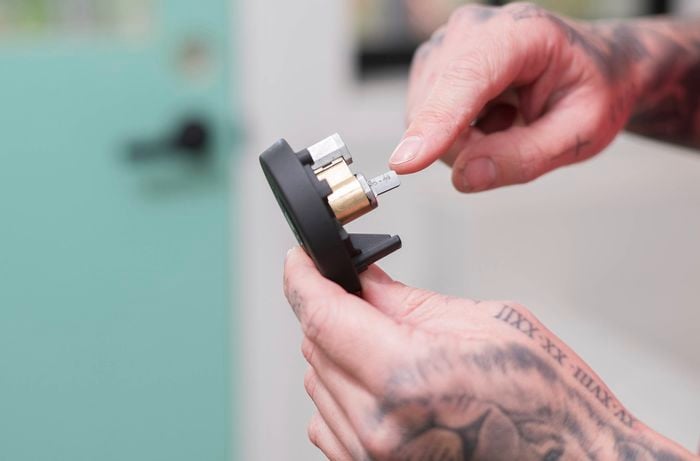 A person is holding a lock cylinder pointing to a specific part of the barrel lock cylinders.