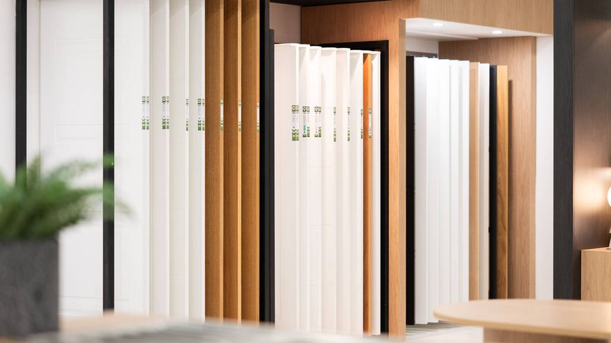 Display of interior door and panel samples in various finishes, presented on sliding showroom racks for material selection.