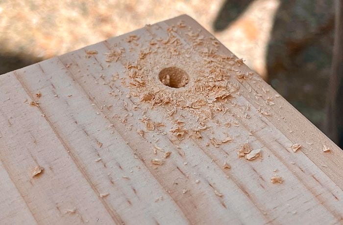 A panel of wood with a hole drilled in the corner.