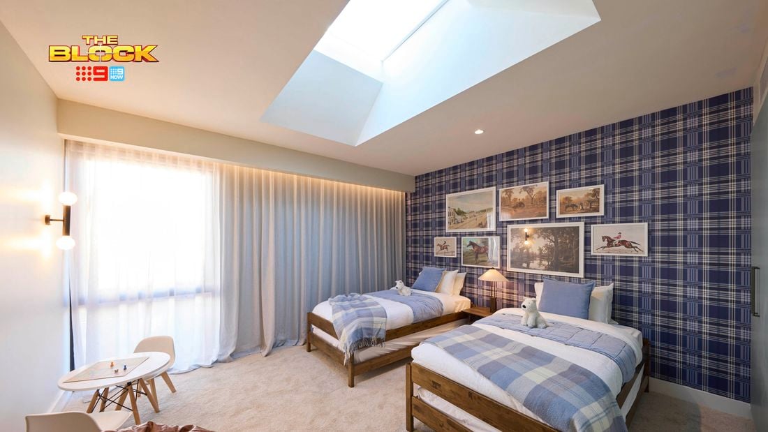 Blue bedroom with a check wallpapered wall and twin beds with blue linens. Opposite is a brown leather bean bag and small kids table. Above the beds are various horse artworks arranged sporadically.