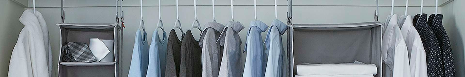 Clothes hanging in wardrobe from hangers and hanging storage container