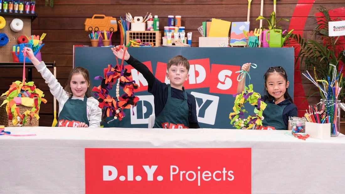 Three kids are holding a beautiful wreath