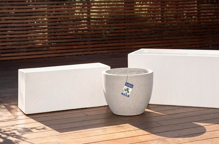 Three modern, empty plant pots are displayed on a wooden deck to select the right style to match the space